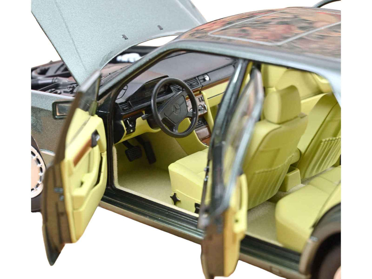 Miniature Mercedes-Benz 230 E diecast model car by Norev, 1/18 scale, in Night Green Metallic with green interior.