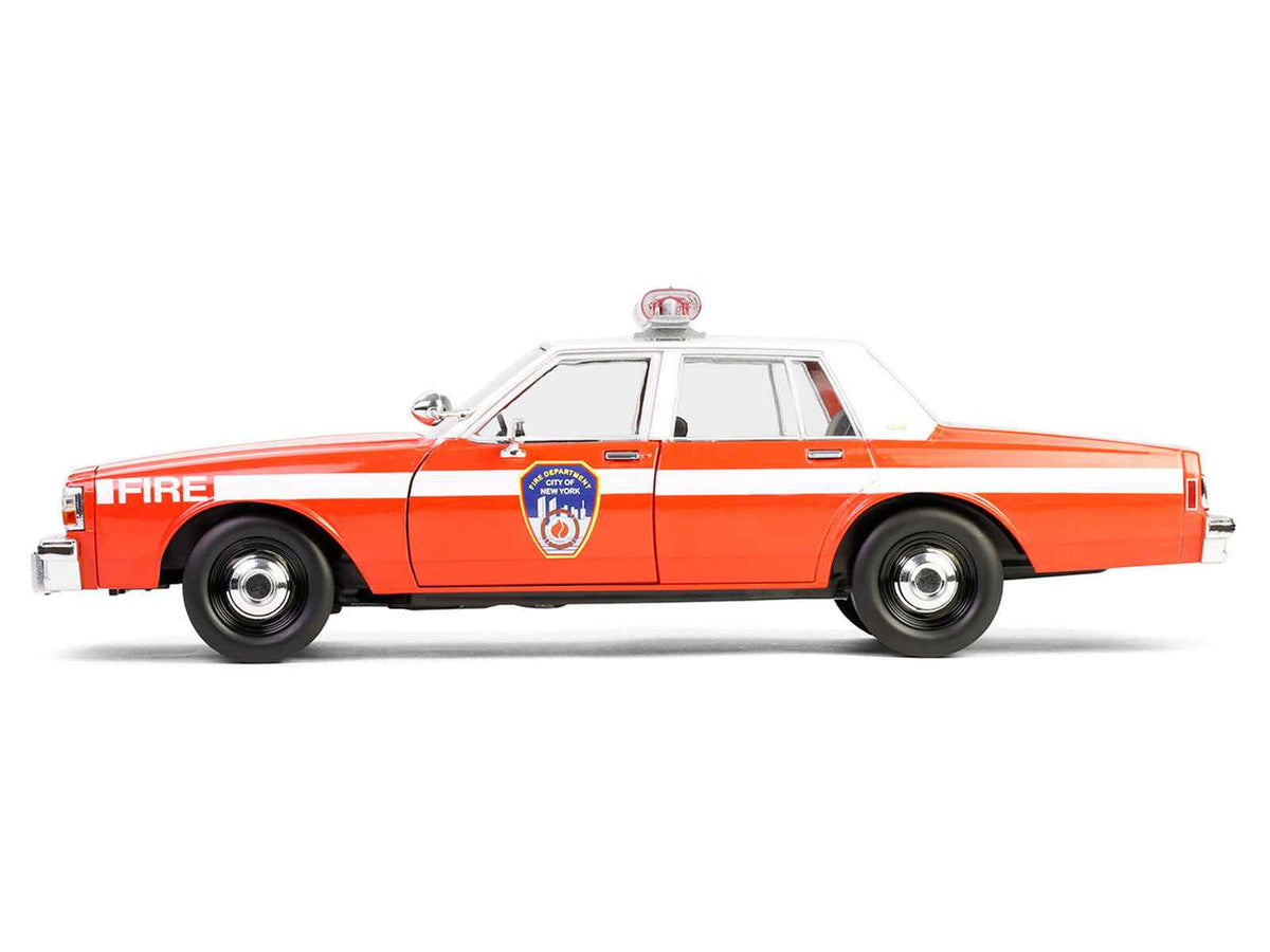 Red 1987 Chevrolet Caprice 9C1 FDNY diecast model car by Greenlight, detailed miniature with white top and fire department stripes.