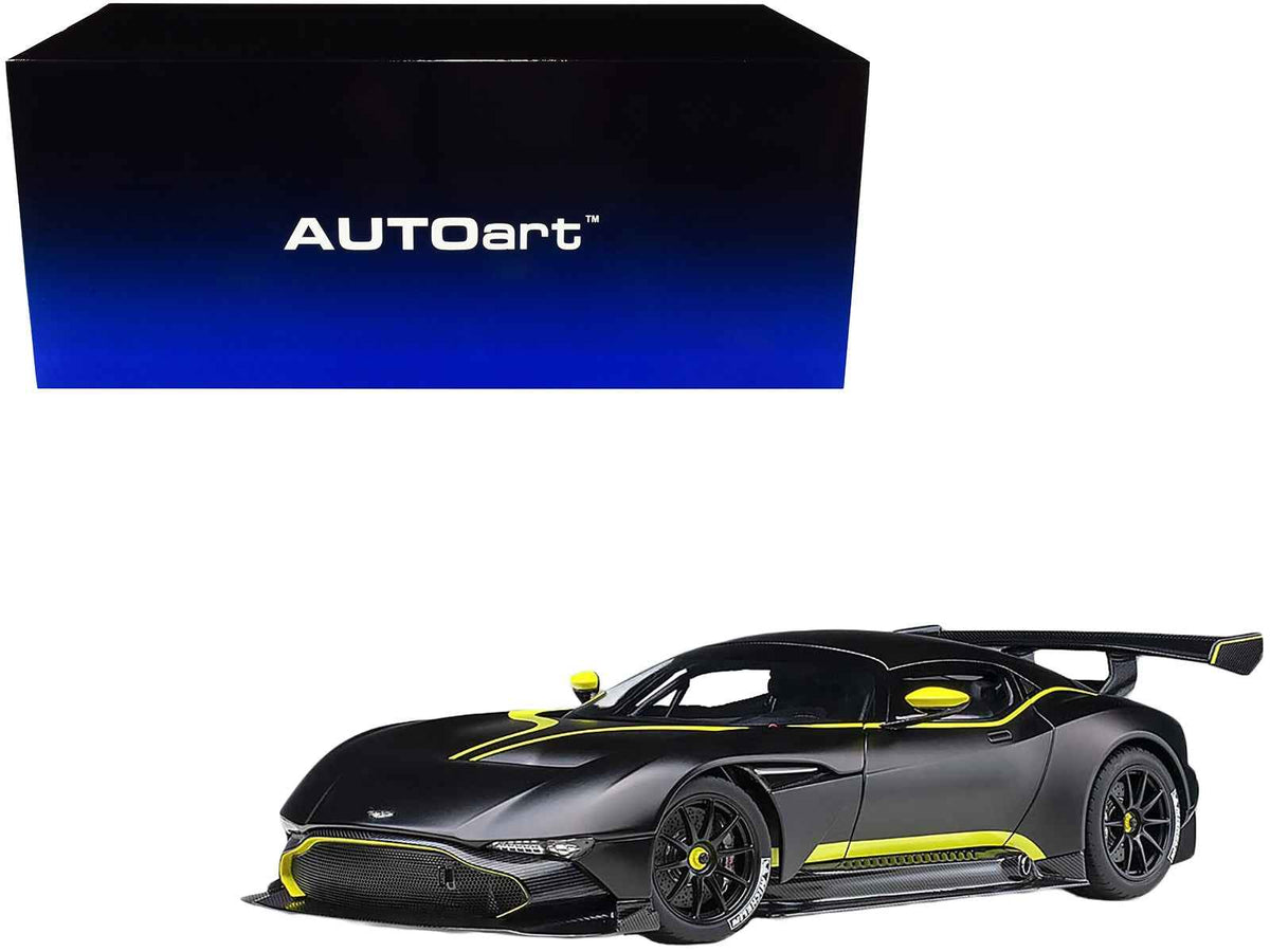 Miniature Aston Martin Vulcan model car in matte black with lime green stripes, 1/18 scale by Autoart, detailed collectible toy.