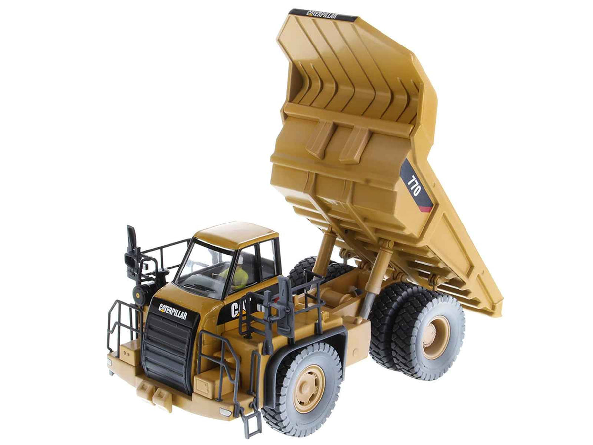 Weathered yellow CAT Caterpillar 770 off-highway truck diecast model by Diecast Masters, detailed construction model with operator figure.