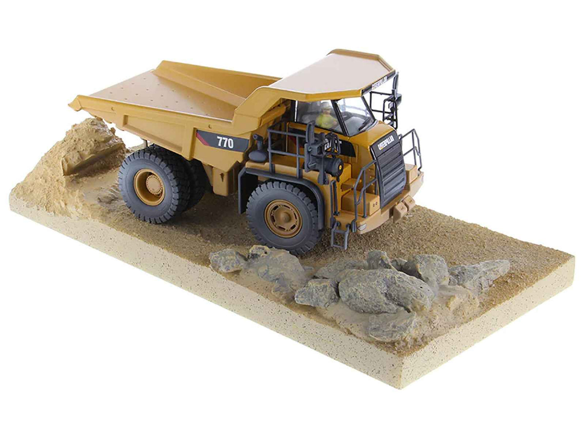 Weathered yellow CAT Caterpillar 770 off-highway truck diecast model by Miniature Motors in operator cab, detailed construction replica.