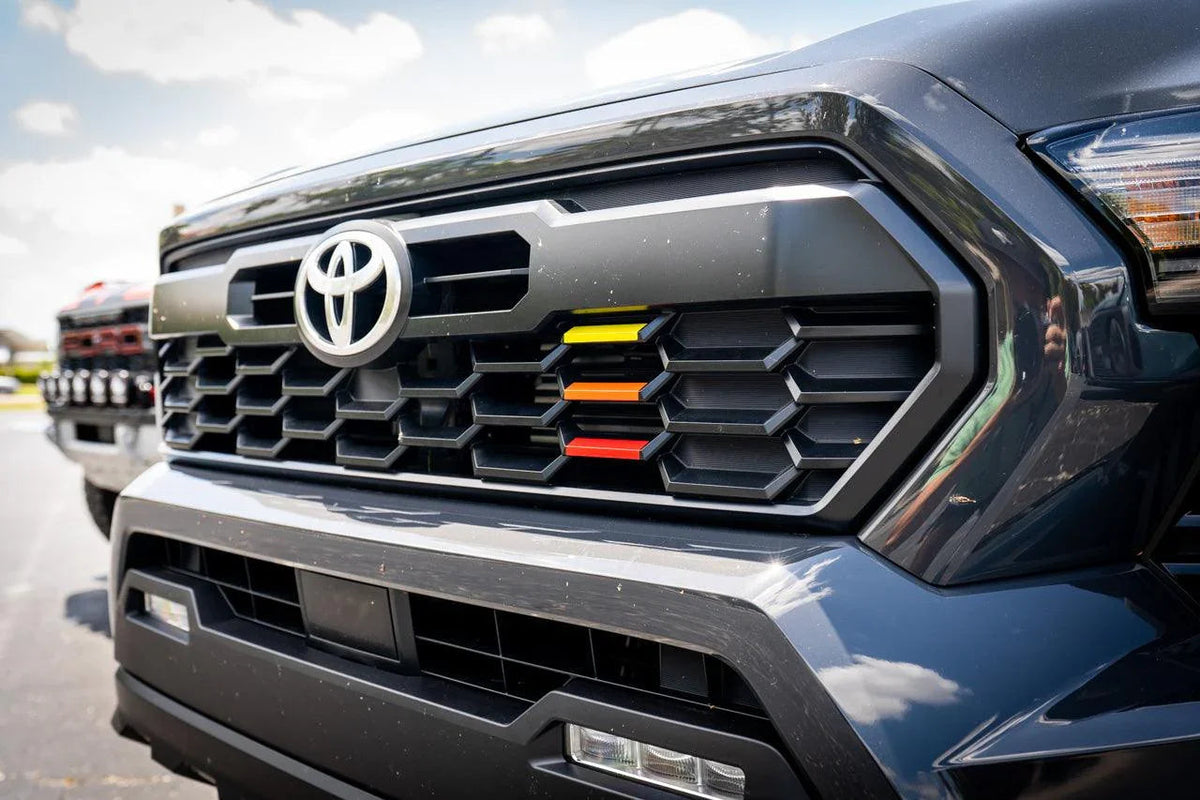 TRD style heritage grille tri bar overlays for 2024+ Toyota Tacoma, vinyl exterior accessory by StickerFab, shown on vehicle.