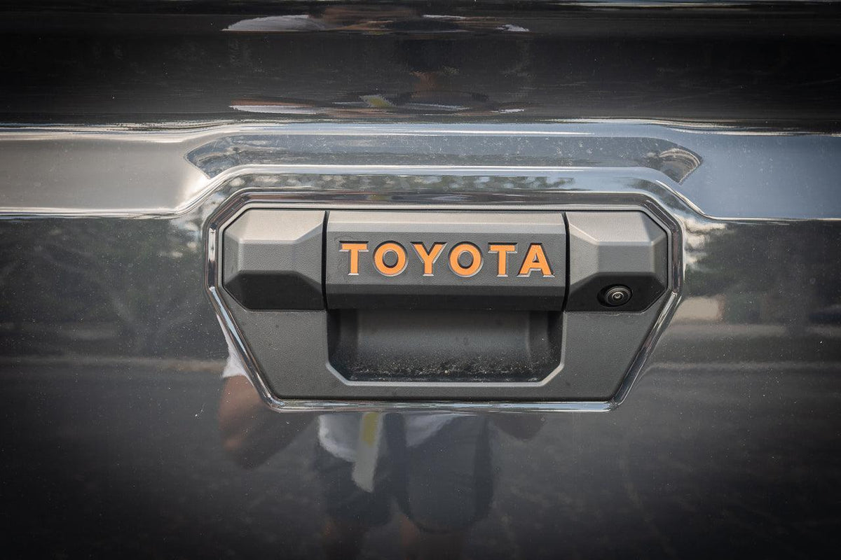 Tailgate handle inlay letters for 2024+ Toyota Tacoma, vinyl exterior decal by StickerFab, shown on vehicle tailgate.