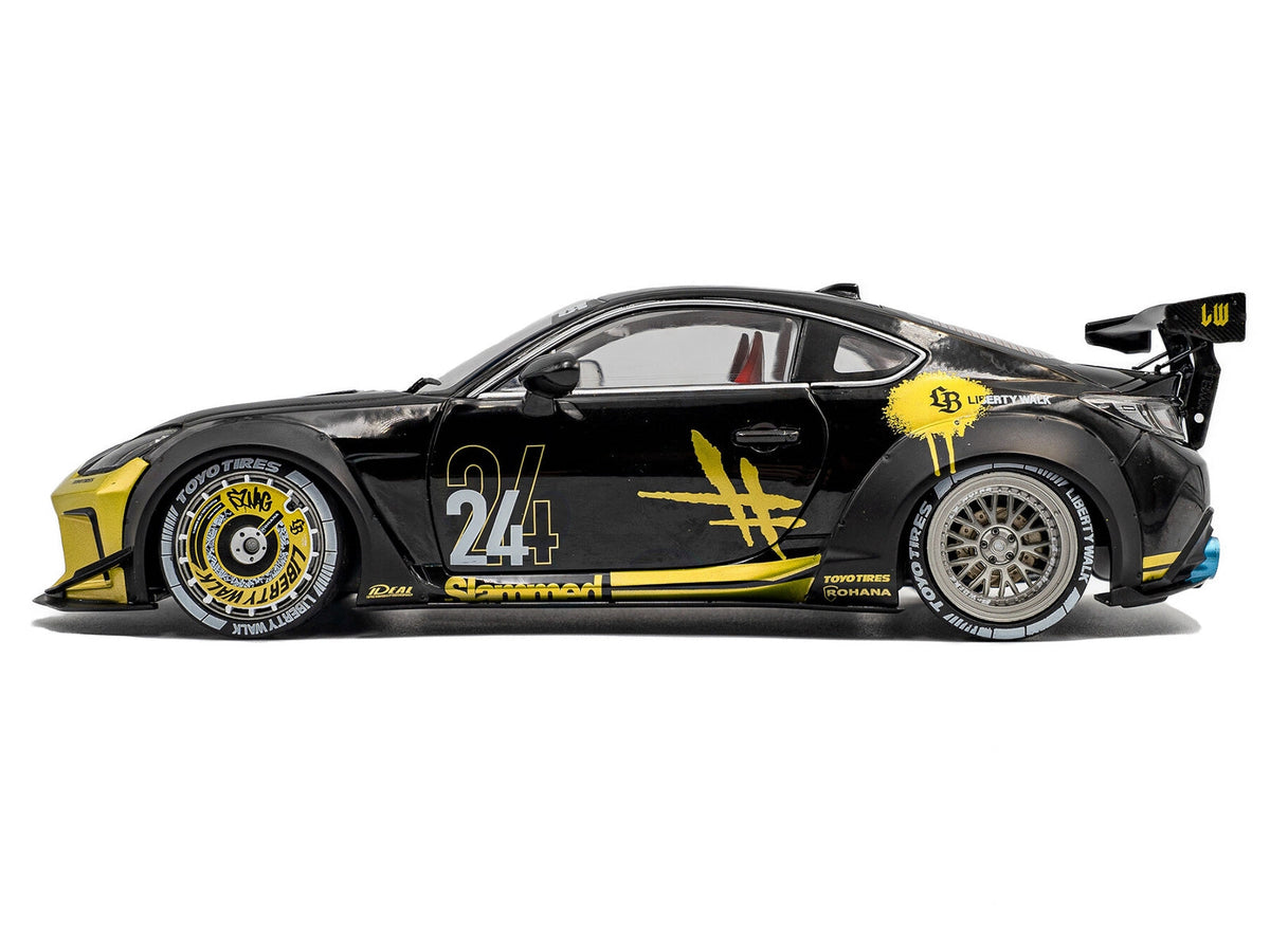 Black 2024 Toyota GR86 Liberty Walk diecast model car with gold graphics, RHD, 1/18 scale by Solido, featuring detailed body kit.