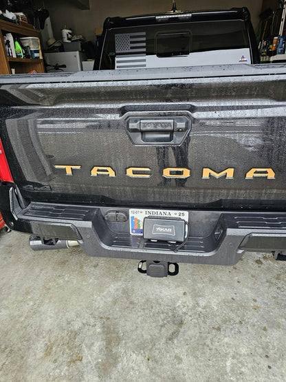 Black vinyl TACOMA tailgate inlay letters for 2024+ Tacoma, exterior automotive decal by StickerFab, shown on vehicle tailgate.