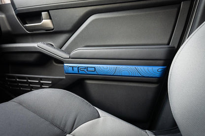Vinyl interior door line overlays for 2024+ Toyota Tacoma, TRD style, installed on vehicle doors showing sleek black finish.