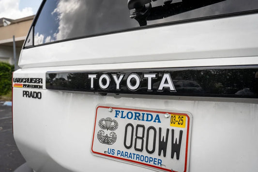 Toyota Land Cruiser 2024+ rear tailgate emblem overlays by StickerFab, close-up of chrome-style emblems on vehicle tailgate.