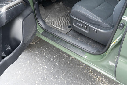 StickerFab Topo Door Sill Protectors for 2016-2023 Toyota Tacoma Double Cab, showing textured metal sill protectors on vehicle door thresholds.