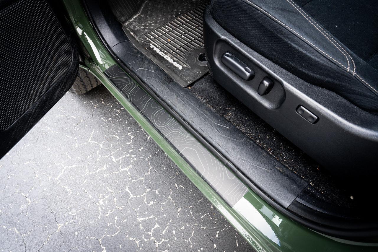 Topo Door Sill Protectors for 2016-2023 Tacoma Double Cab by StickerFab, showcasing black door sill protectors on vehicle thresholds.