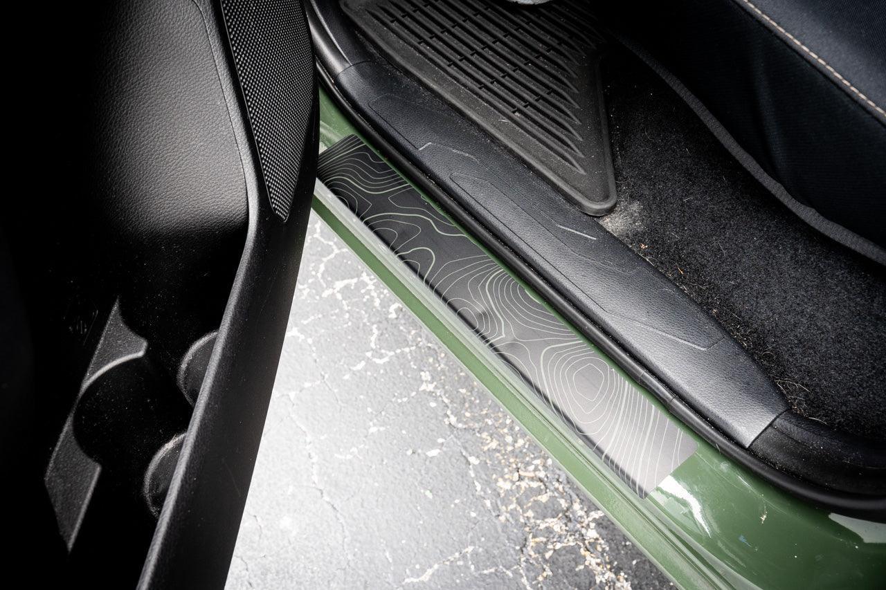 StickerFab Topo Door Sill Protectors for 2016-2023 Tacoma Double Cab, close-up of durable metal sill protectors with topo design.