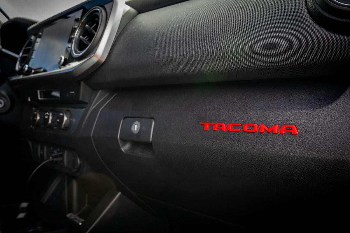 Tacoma glove box with acrylic "TACOMA" logo inlays from StickerFab's Laser Series, featuring interior vinyl accents for 2016-2023 models.