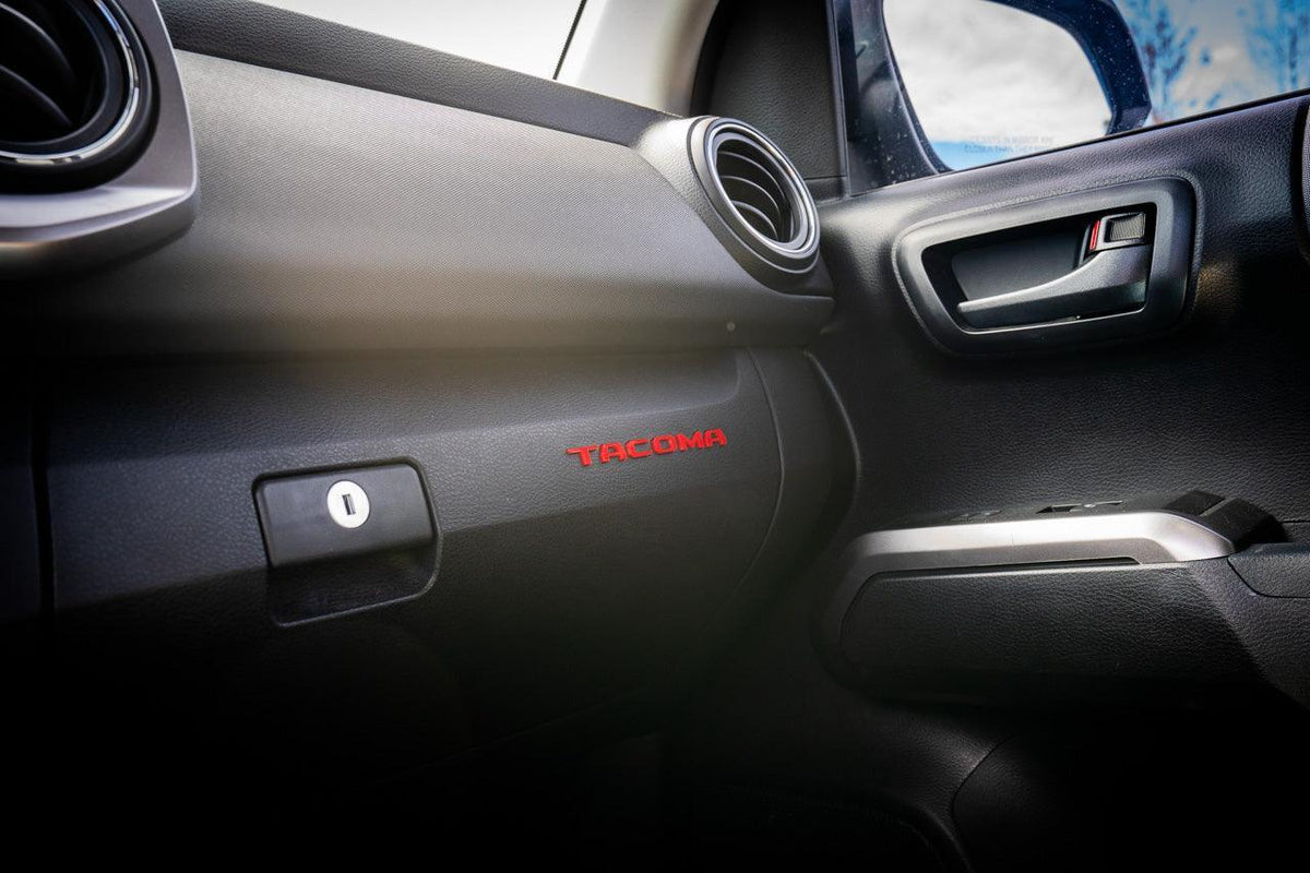 Tacoma glove box with acrylic "TACOMA" logo inlays from StickerFab's Laser Series, interior vinyl accessory for 2016-2023 Tacoma.