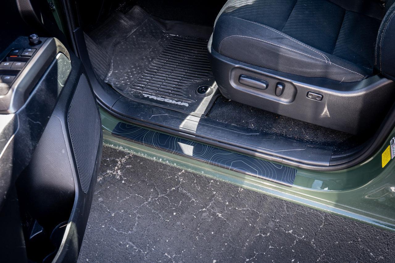 StickerFab Topo Door Sill Protectors for 2016-2023 Toyota Tacoma Double Cab, close-up of textured black and gray door sill guards.