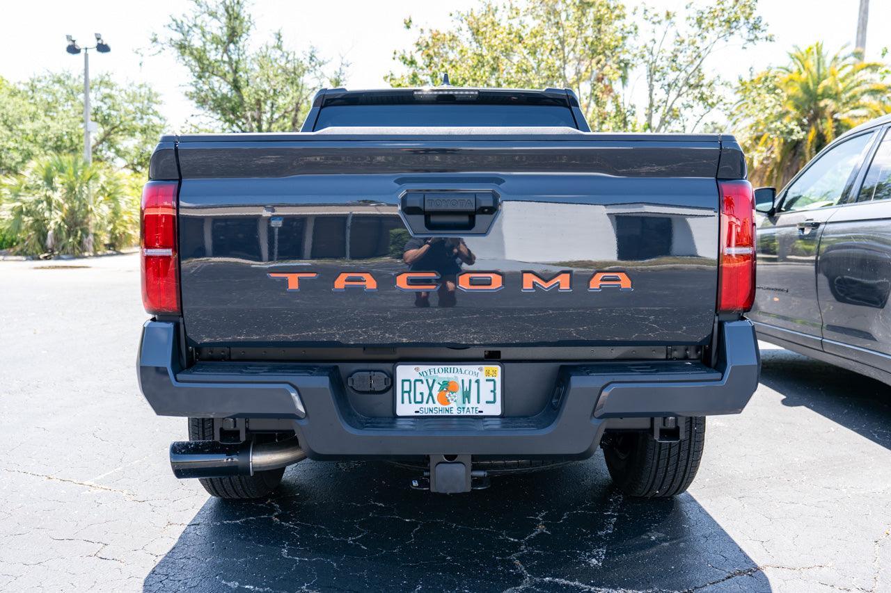 Black vinyl TACOMA tailgate inlay letters for 2024+ Tacoma, exterior decal by StickerFab, shown on vehicle tailgate.