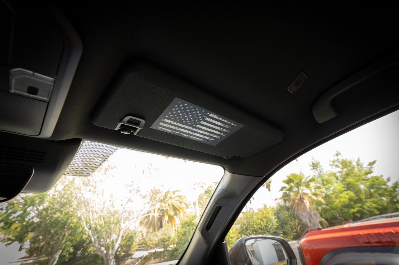 Sun visor airbag label with distressed American flag overlay on 2024+ Toyota Tacoma interior vinyl, by StickerFab.