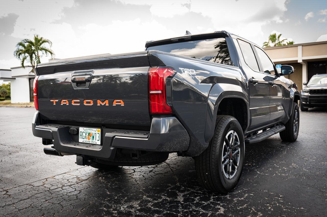 2024+ Toyota Tacoma tailgate handle inlay with standard vinyl letters, exterior StickerFab decal on vehicle tailgate.