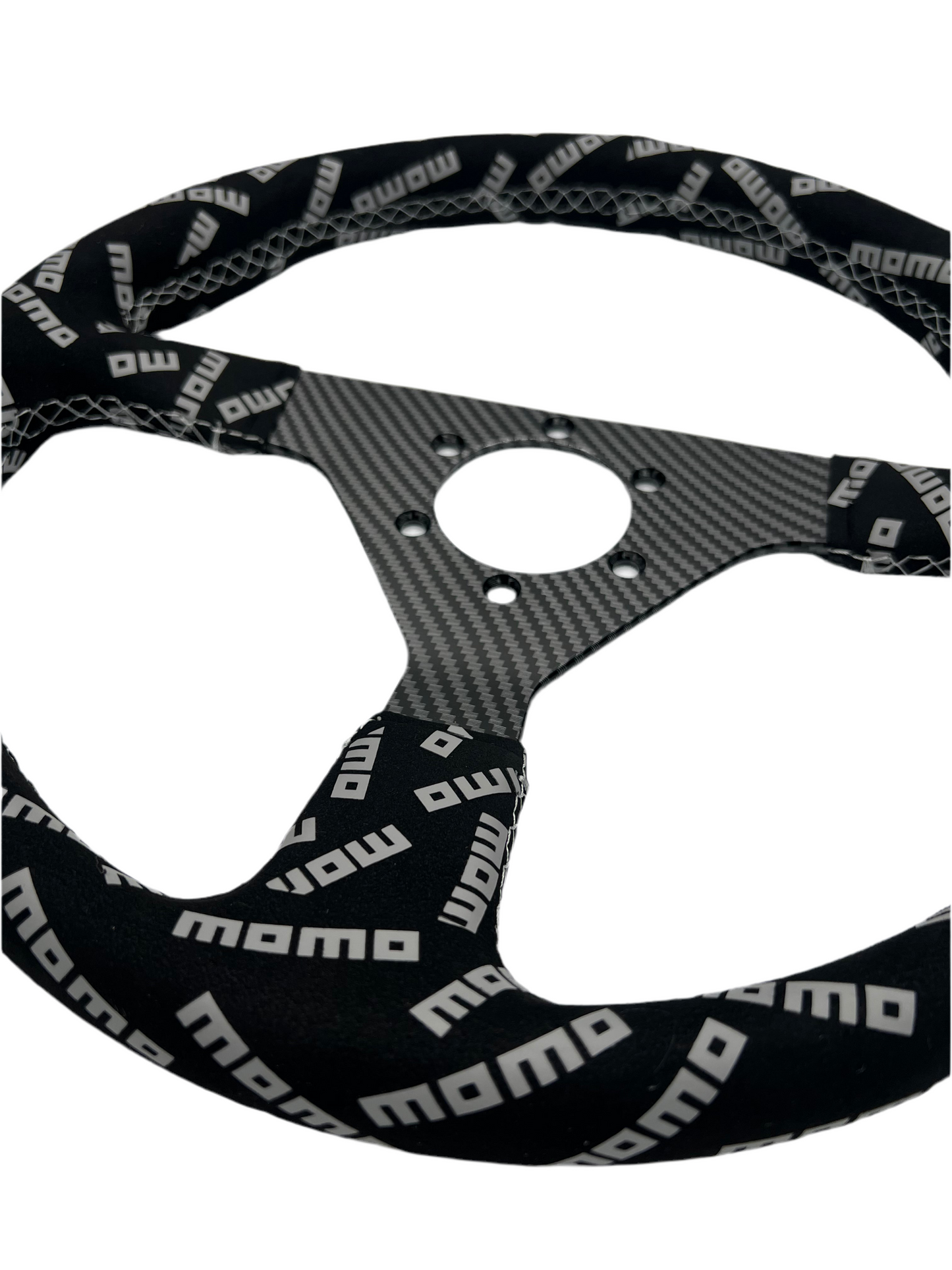 Black suede racing steering wheel with carbon center from Momo, designed for performance driving by Speedzone Performance LLC.