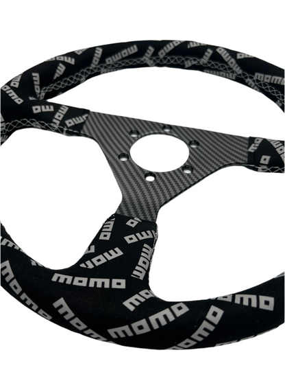Black suede racing steering wheel with carbon center from Momo, designed for performance driving by Speedzone Performance LLC.