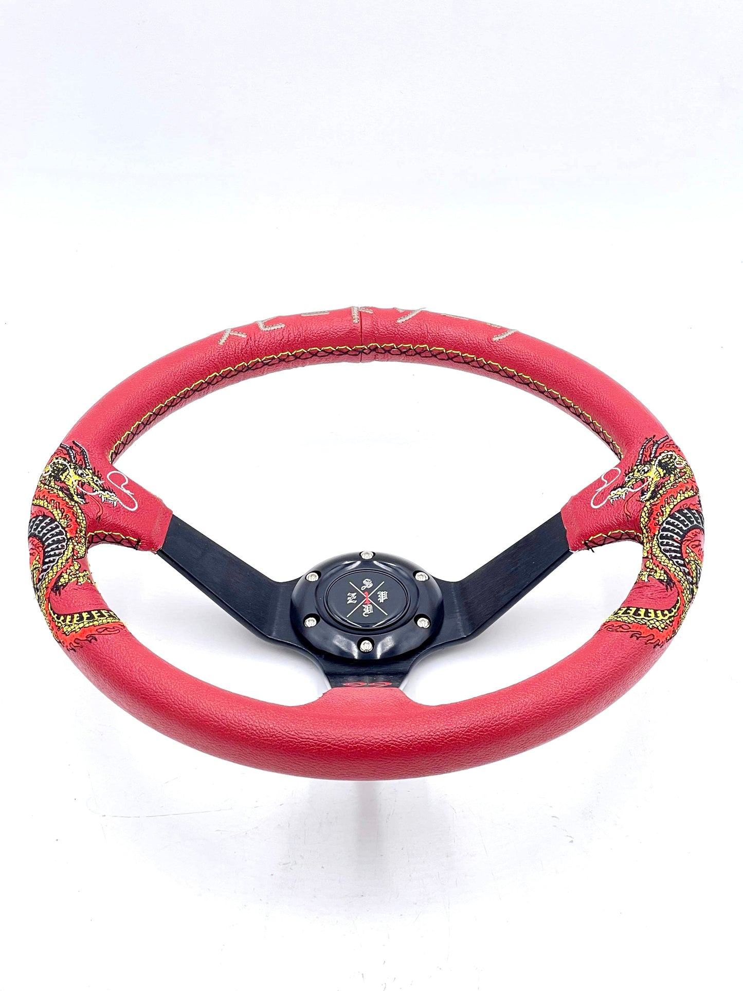 Red SPDZ1 “The Dragon” steering wheel by Speedzone Performance LLC, showing the detailed dragon design and textured grip.