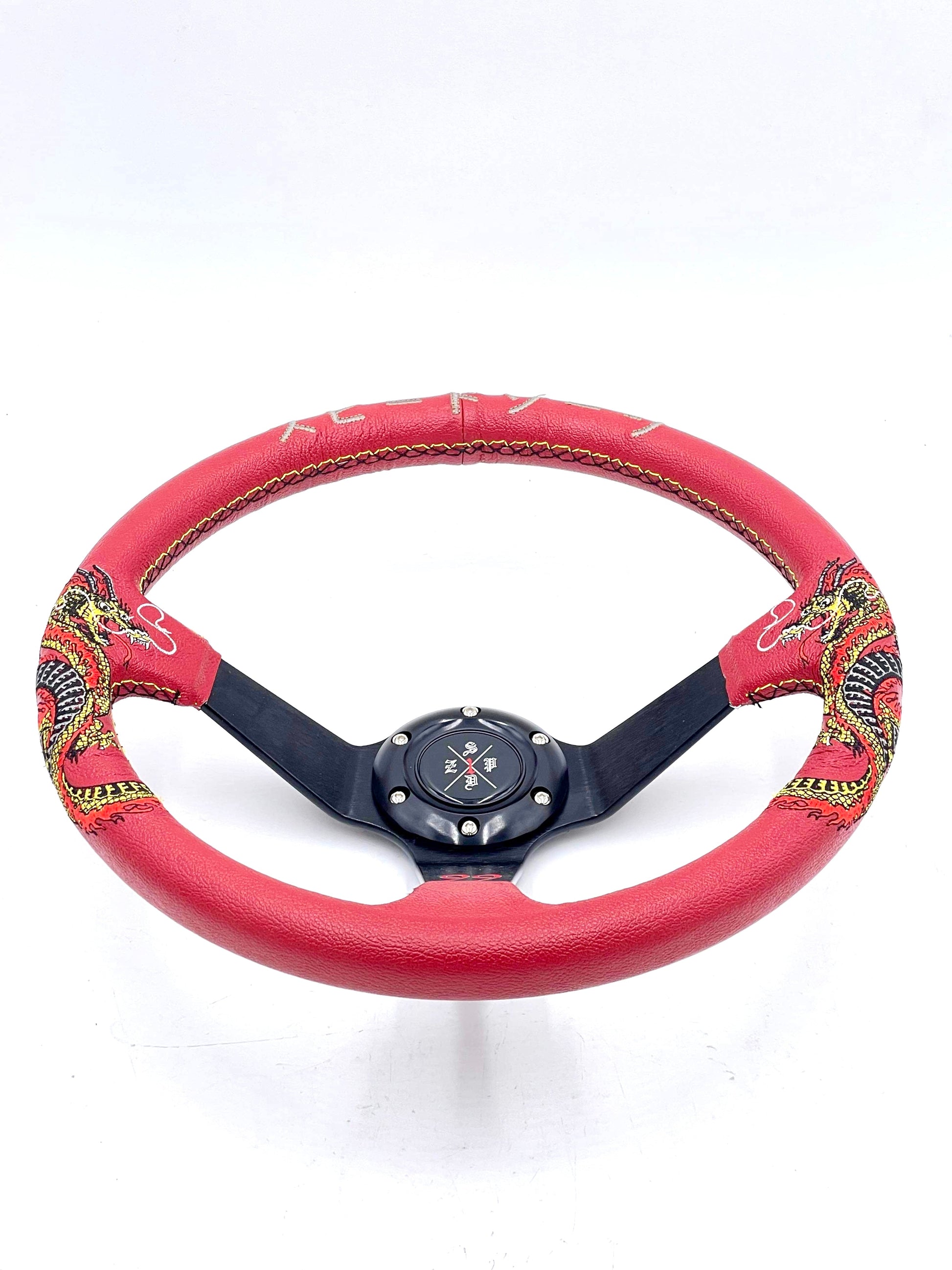 Red SPDZ1 “The Dragon” steering wheel by Speedzone Performance LLC, showing the detailed dragon design and textured grip.