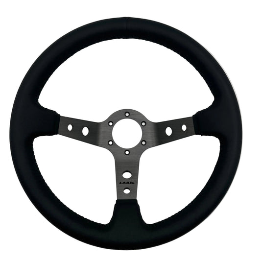Black leather Daytona steering wheel with graphite spoke and black stitching, designed for performance cars.