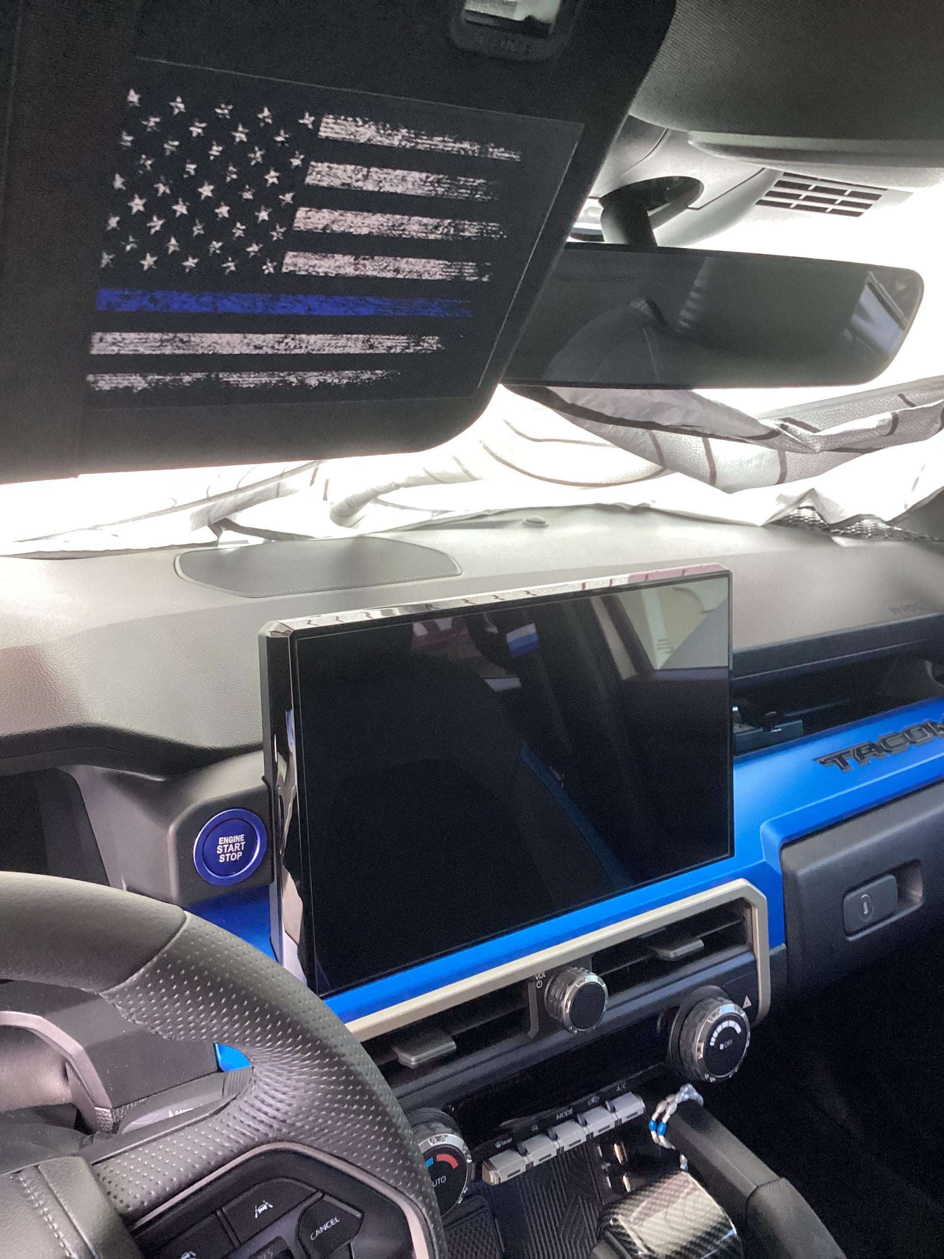 Sun visor airbag label with distressed American flag overlays on vinyl interior for 2024+ Toyota Tacoma, by StickerFab.