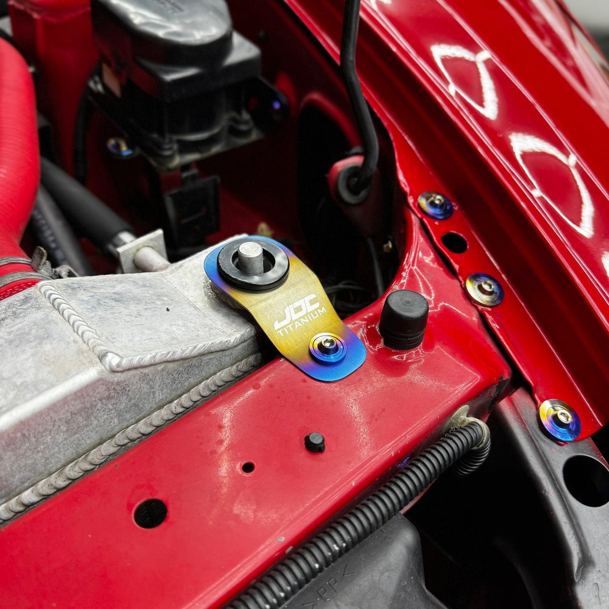 Titanium radiator stay bracket for Honda S2000, EK, EM, and EJ models by JD Customs U.S.A, showcasing a sleek, lightweight design.